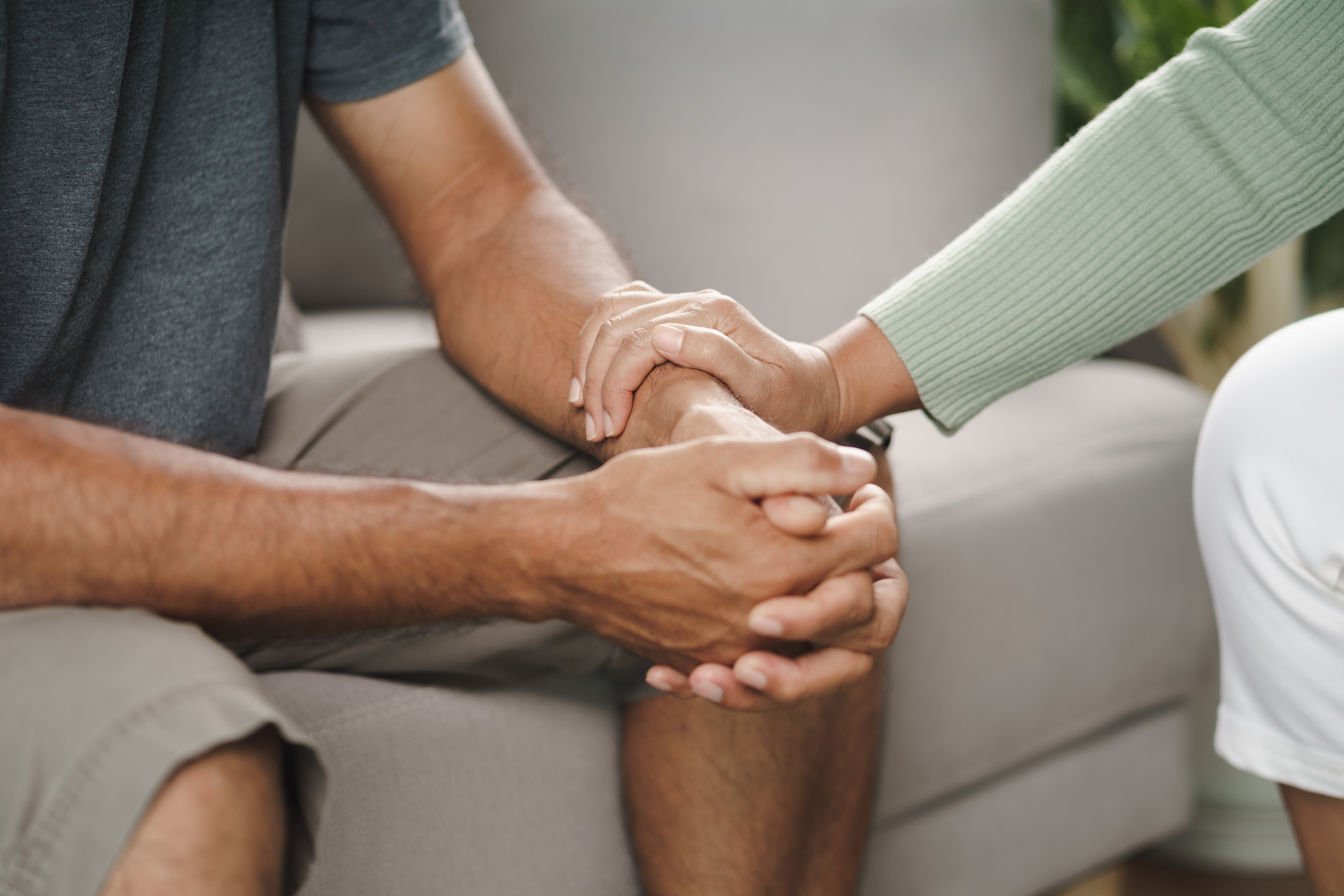 Une personne assise serre le bras d'une autre personne assise en face pour la réconforter