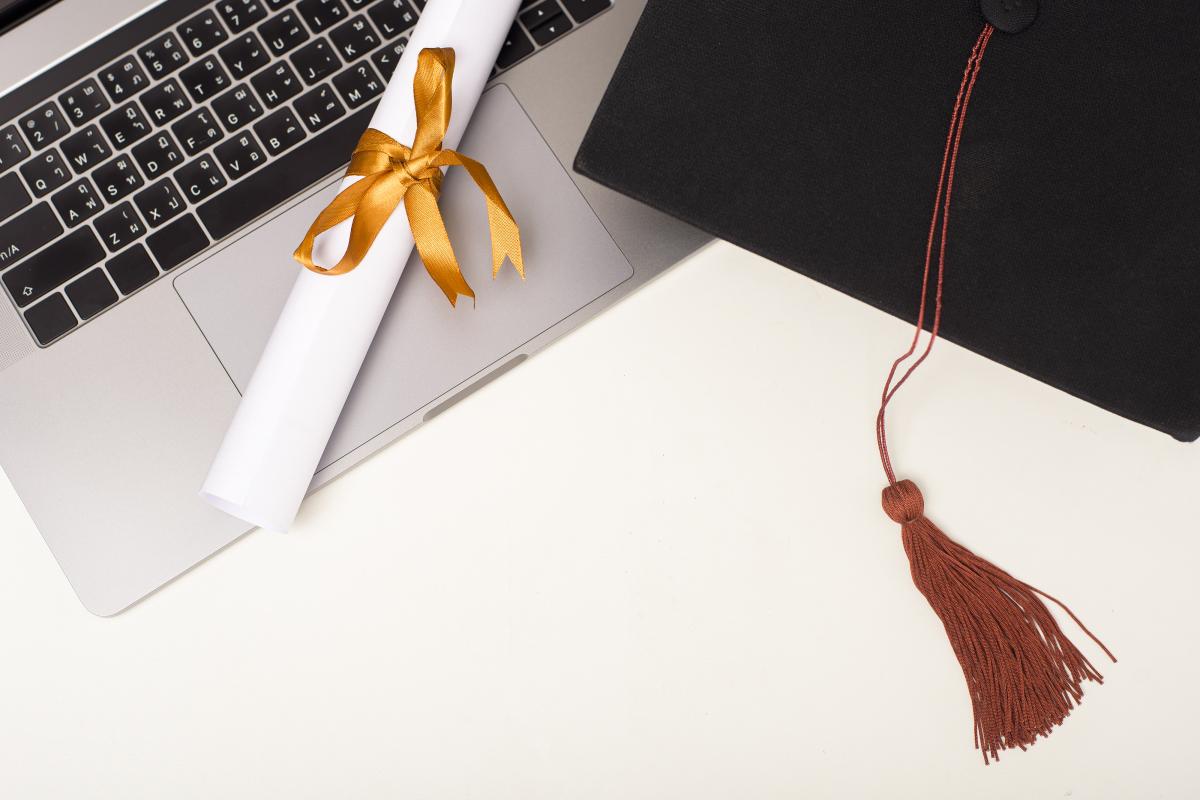 Un ordinateur, un diplôme et un chapeau de diplômé
