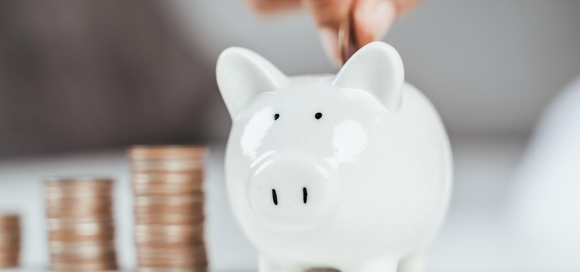 Main insérant une pièce de monnaie dans une tirelire cochon