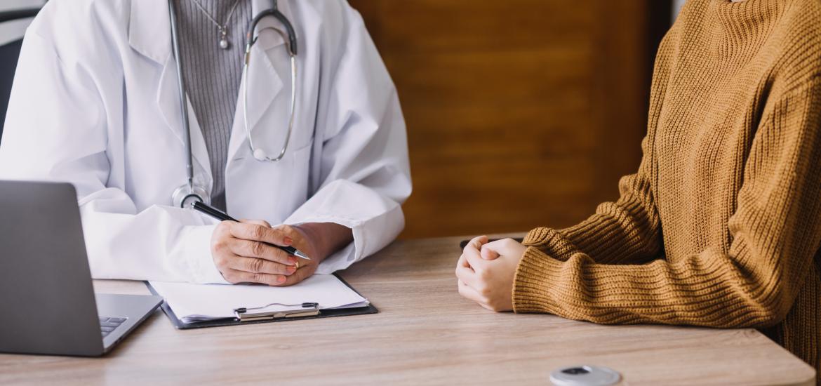 Une personne en blouse blanche fait une consultation avec une personne vêtue d'un pull
