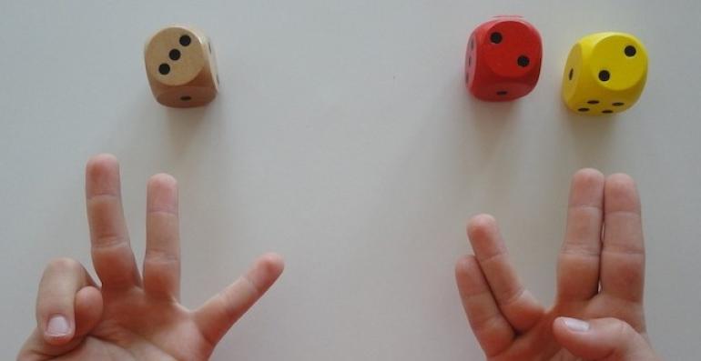 photo : à gauche : un dé avec un 3 et une main avec 3 doigts levés ; à droite : 2 dés avec un 2 et un 2 et une main avec 2*2 doigts levés (annulaire et auriculaire collés l'un à l'autre, majeur et index collés l'un à l'autre) 