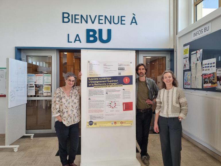3 collègues posent devant un panneau d'expo à la BU Bouguen
