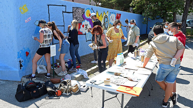des gens dessinent sur un mur bleu