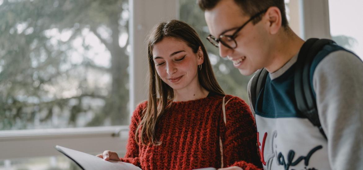 Deux étudiants qui regardent un cahier. 