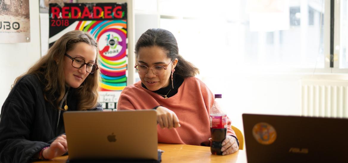 Deux étudiantes qui travaillent sur un ordinateur dans un local associatif. 