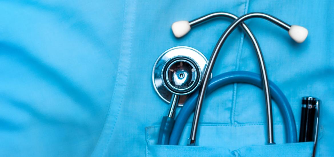 Zoom sur une poche de blouse médicale bleue, laissant dépasser un stétoscope