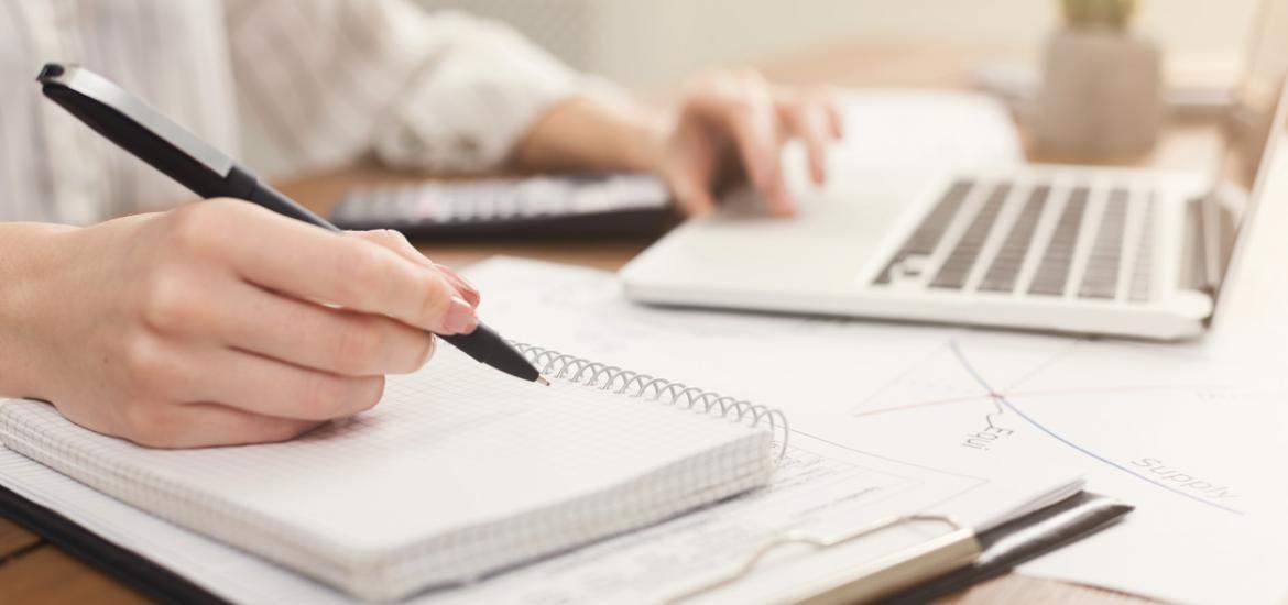 Image d'illustration d'une personne en train de travailler sur un bloc note et un ordinateur